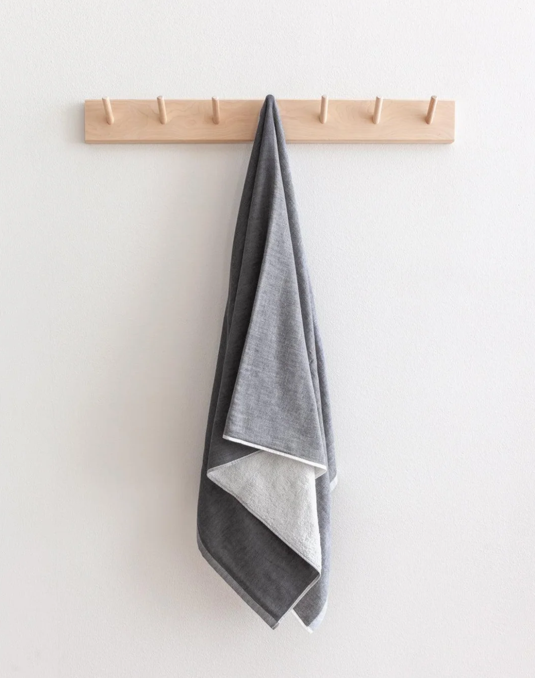 Black two-tone chambray towel hanging from a wooden peg