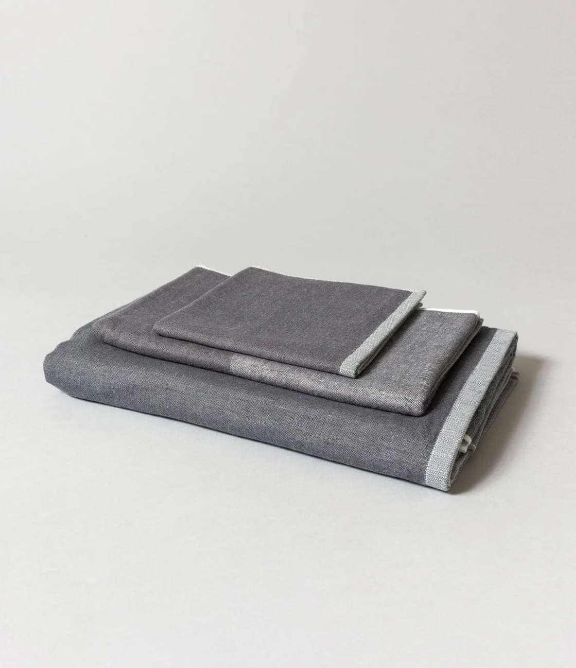 Three black two-tone chambray towels folded in a stack